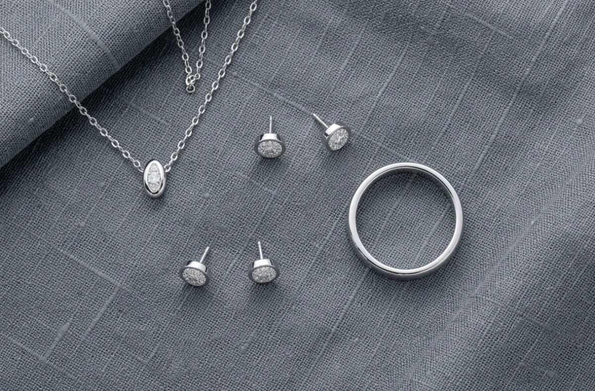 Plat posé de bijoux en or blanc avec diamants pavé sur tissu lin gris ardoise, montrant la collection complète d'une parure fine